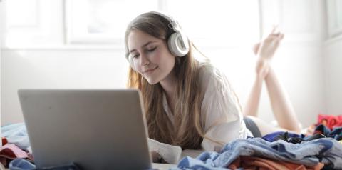 young woman with headphones on watching something on her computer