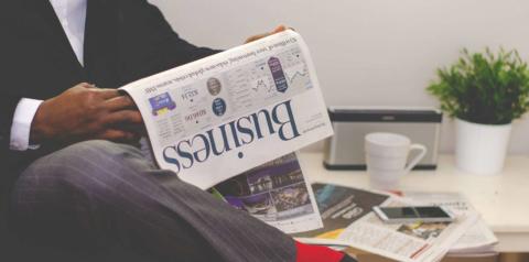 someone sitting reading a business newspaper